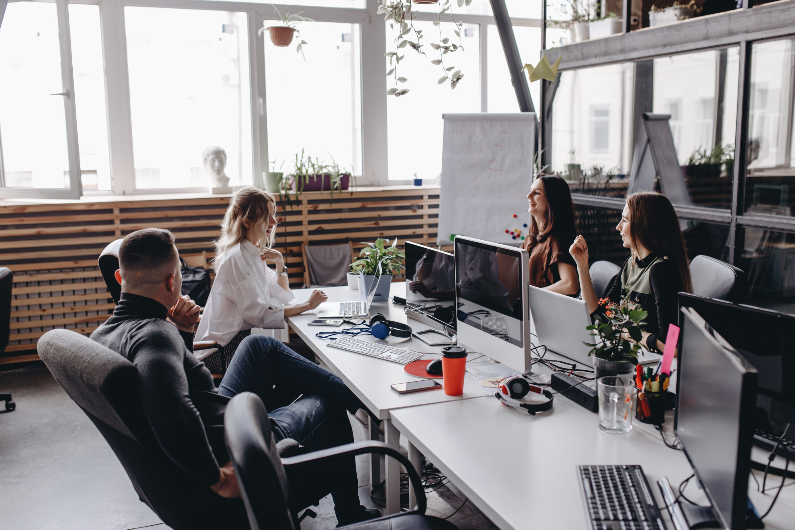 Young team works in a spacious light modern open space office sitting at a desks with a computer and laptops .